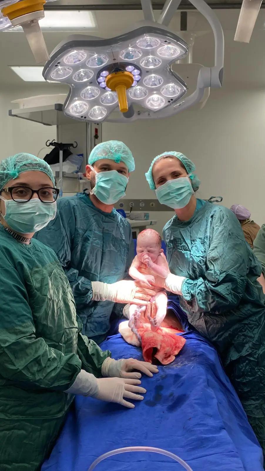 Başarılı bir doğum sonrası , ameliyatı gerçekleştiren doktorlar ve bebek